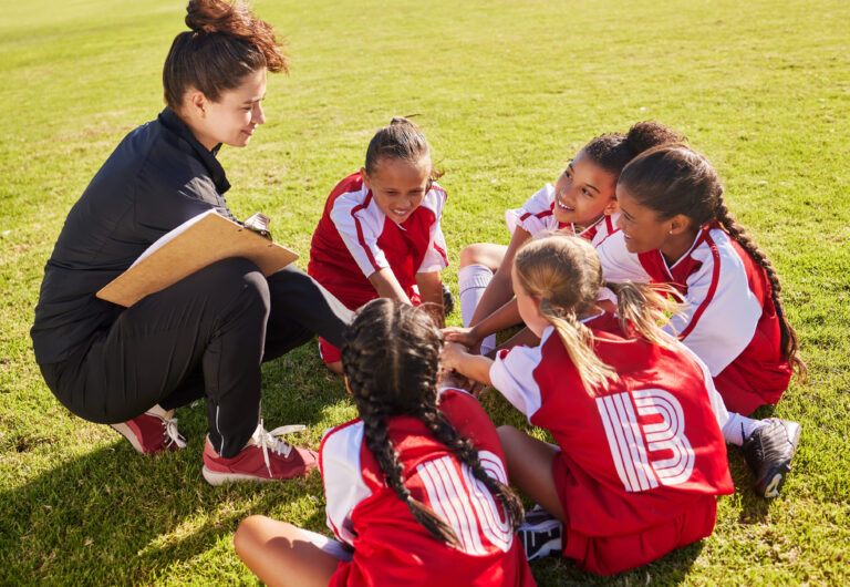 Huddle, sport or coach with children hands for soccer strategy training or team goals in Canada. Team building, circle or woman and group of girls on football field for game support, match or workout.