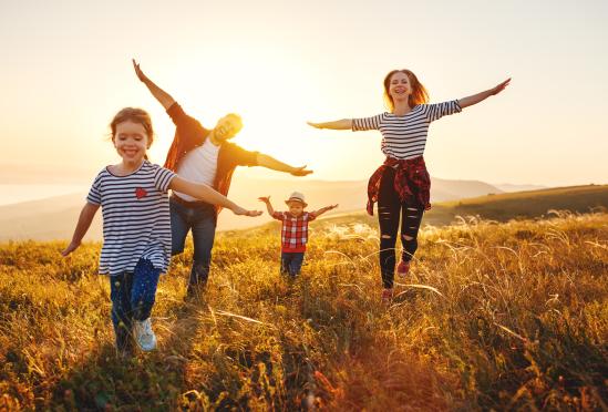 A family running outside with their arms out