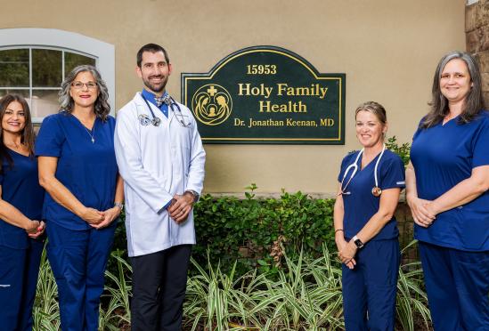 A group photo of the providers beside the locations sign